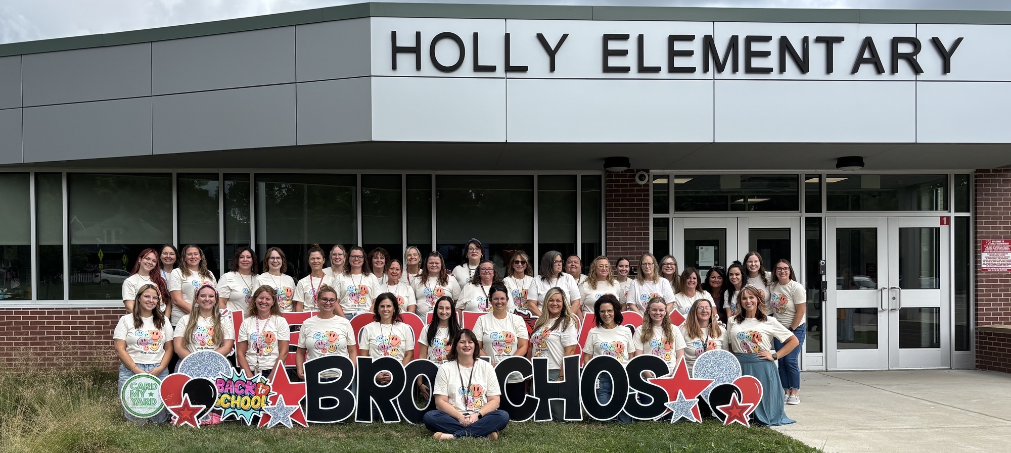 Holly Elementary Staff 25-26 posing in front of the building with Welcome Back Bronchos signage