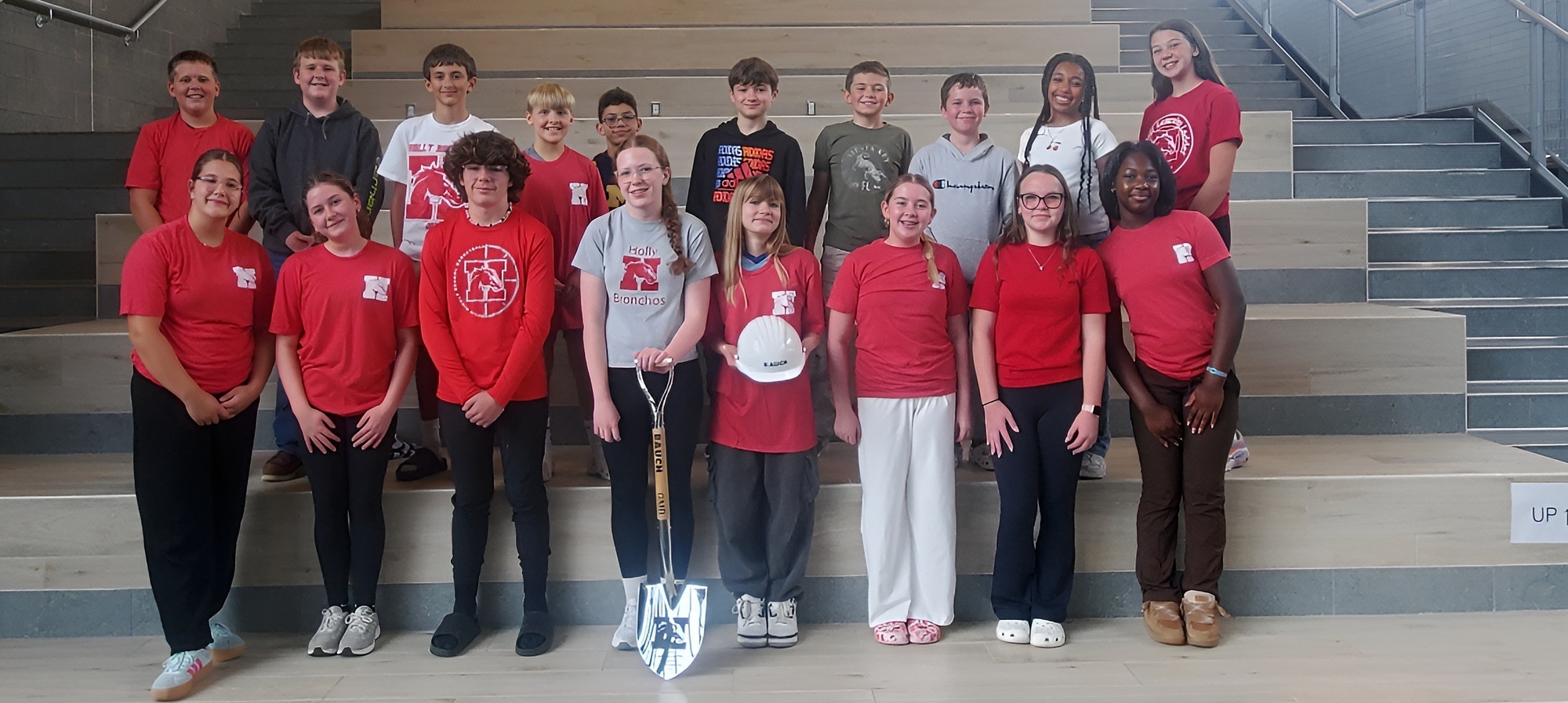 Students at the middle school holding a shovel and hard hat